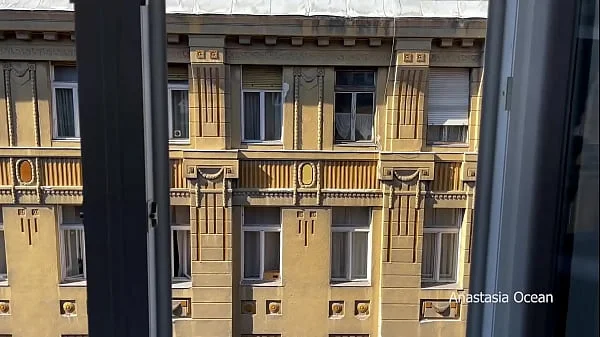 A woman undresses on a balcony in the city center. Public flashing.